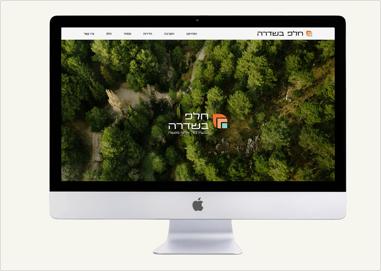 ה-iMac מציג אתר אינטרנט עם תמונת אוויר של יער וטקסט בעברית המופיעה מעל העצים.